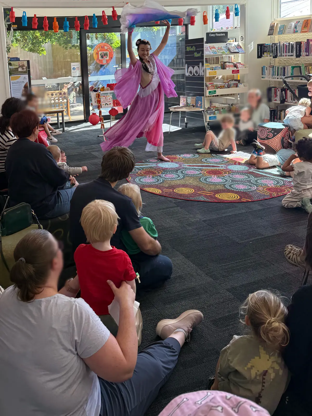 Raina dancing in a library while children and families watch