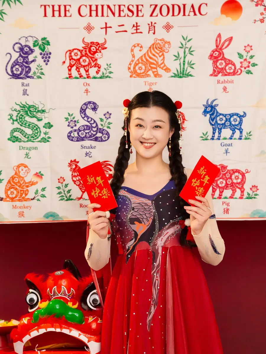 Raina holding red envelopes in front of a Chinese zodiac backdrop