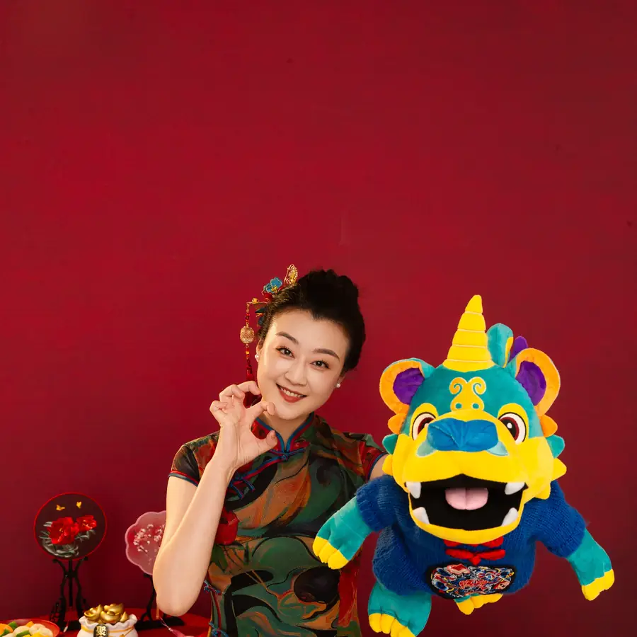 Raina in a floral qipao with a colourful lion puppet