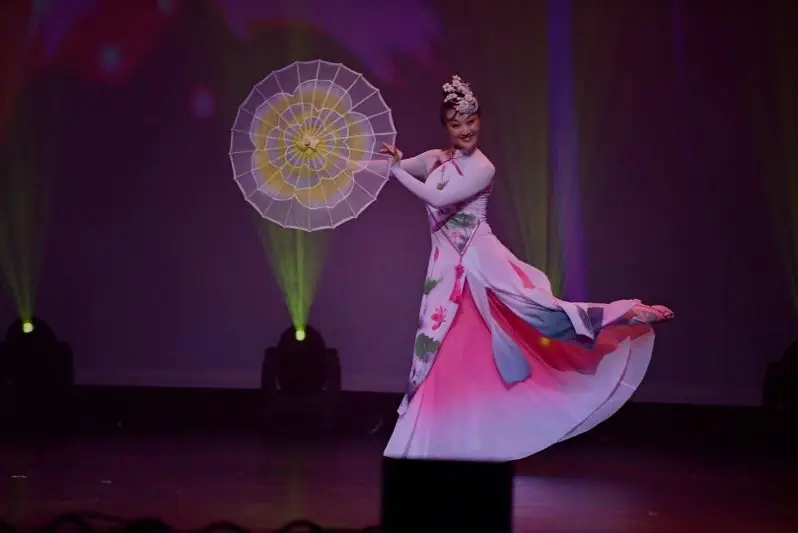 Raina dancing with a parasol on stage