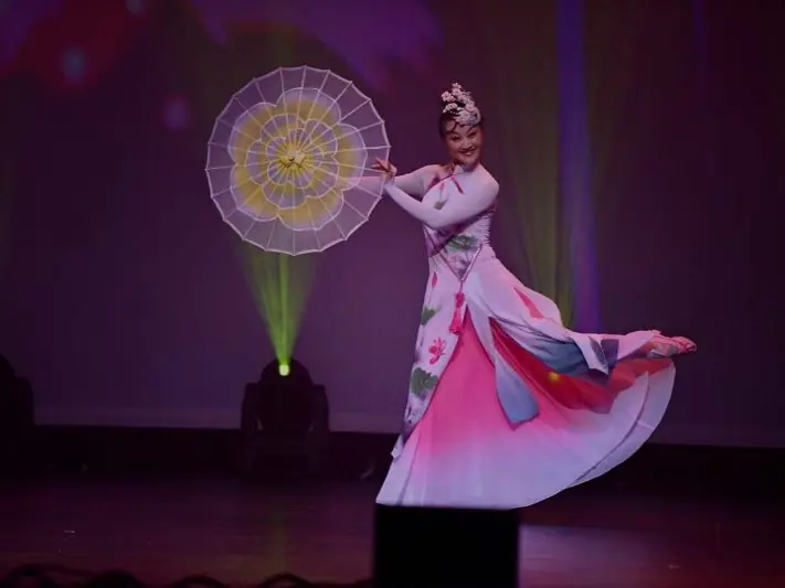 Raina dancing with a parasol on stage